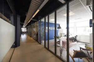 Moderne kantoorruimte aan de Anthony Fokkerweg met glazen wanden en zicht op een ingerichte werkplek.